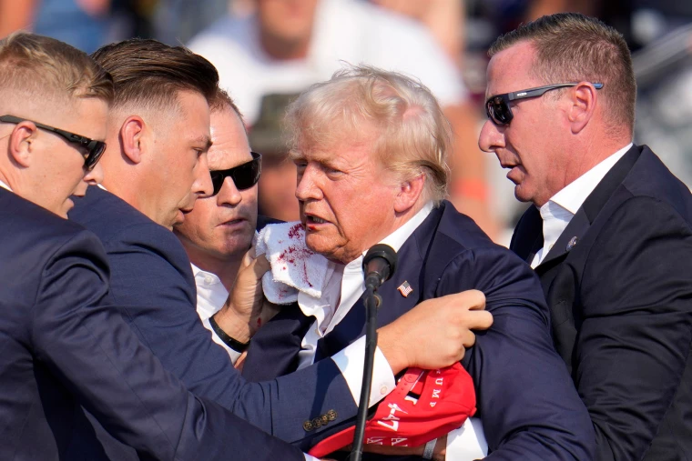 Security personnel surround former President Trump at a rally